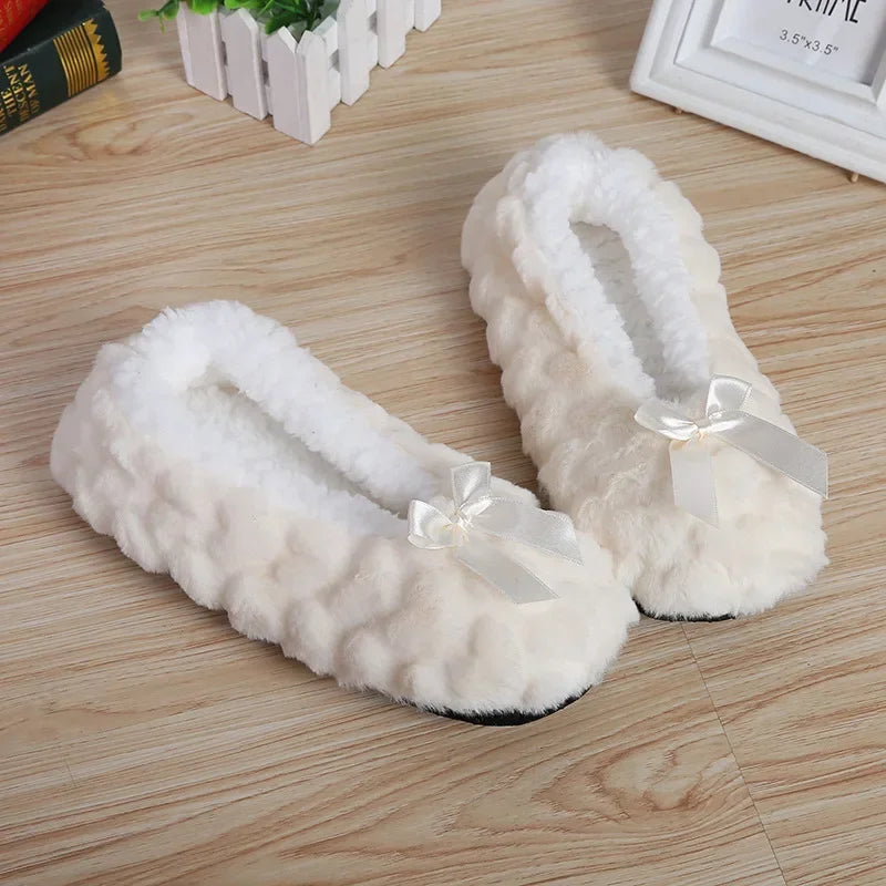 Plush white indoor slippers with bows on wooden floor, cozy loungewear essentials