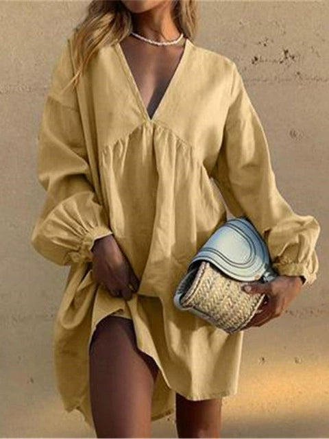 Woman in cozy beige loungewear dress holding woven clutch, neutral backdrop
