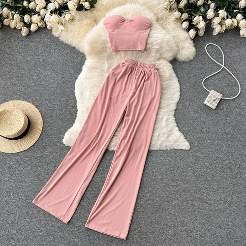 Concierge Tiers displayed with images: pink loungewear set featuring strapless top and wide-leg pants, accessorized with a straw hat and pearl bag on a soft rug background.