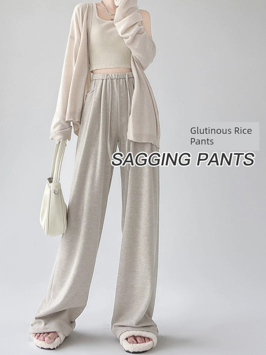 Woman in beige loungewear set with elastic waist sagging pants, slippers, and white handbag.