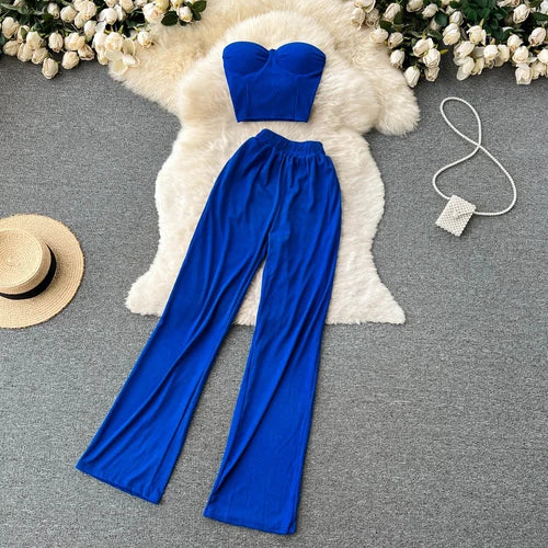 Blue lounge set with strapless top and wide-leg pants, displayed on faux fur rug, with accessories