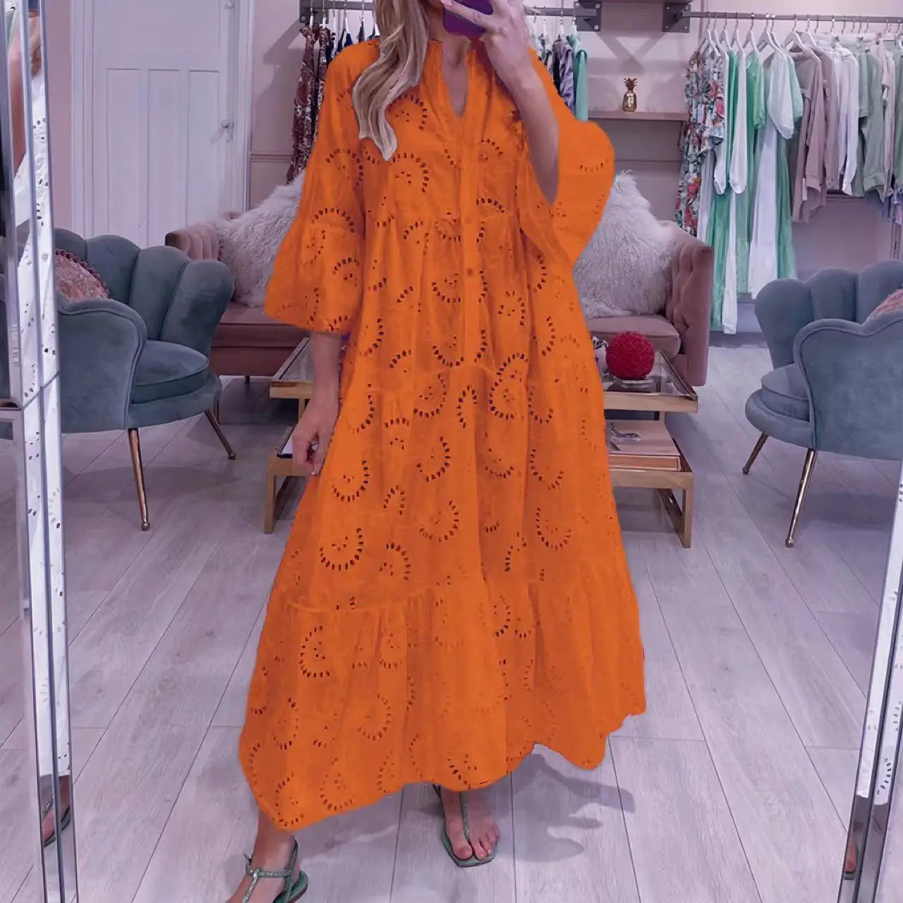 Orange eyelet tiered maxi dress with bell sleeves, cozy boutique setting
