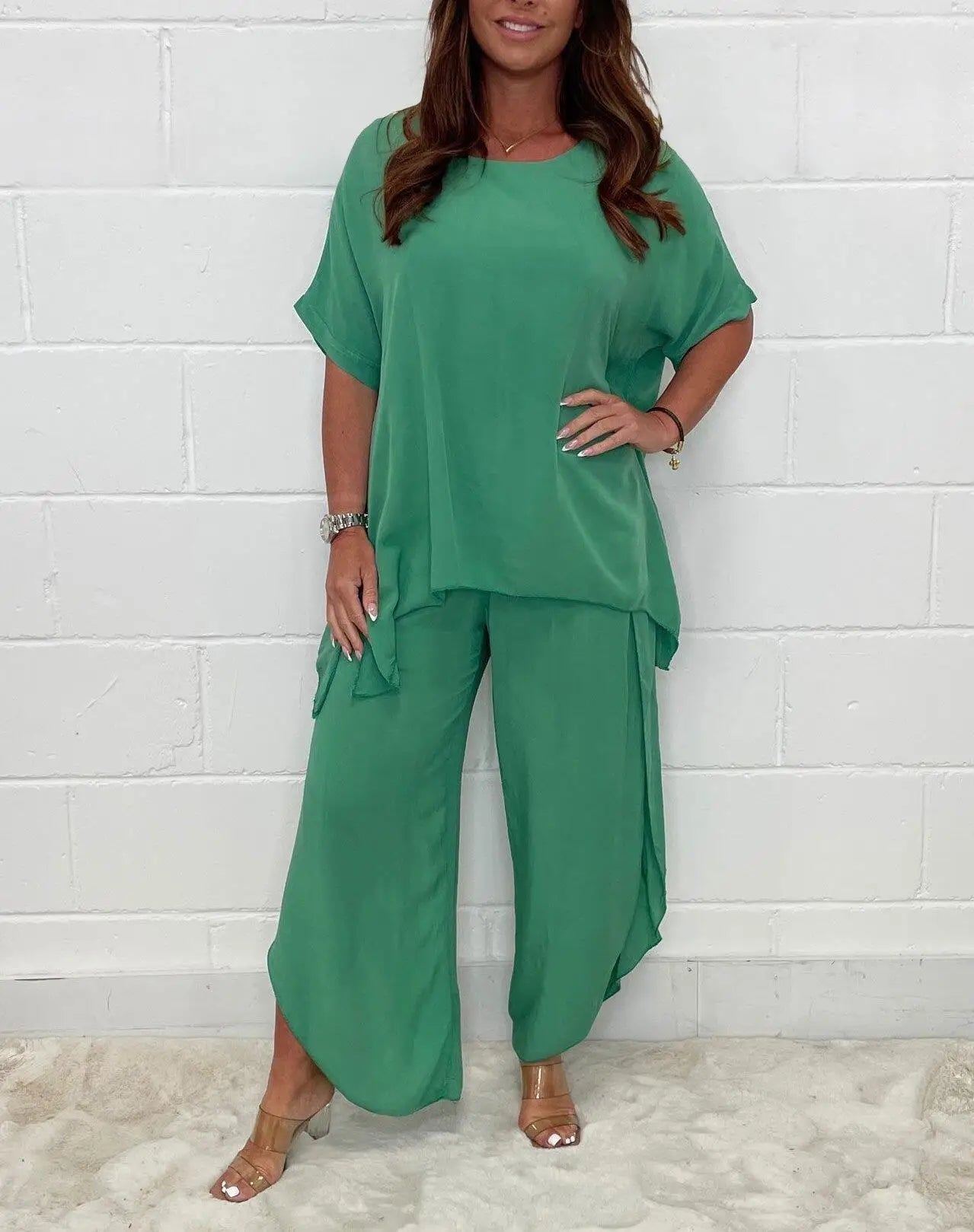Woman wearing loose green loungewear set with short sleeves and wide-leg pants, clear heels