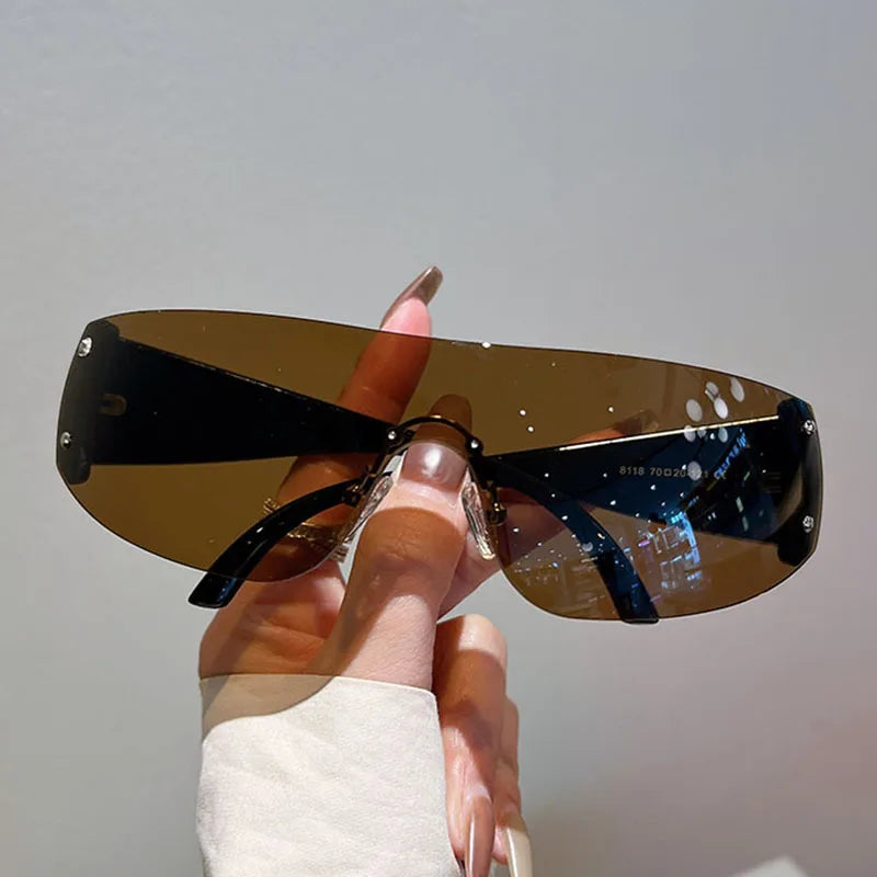 Stylish oversized sunglasses with brown lenses and black frame, held by hand in cozy white sleeve