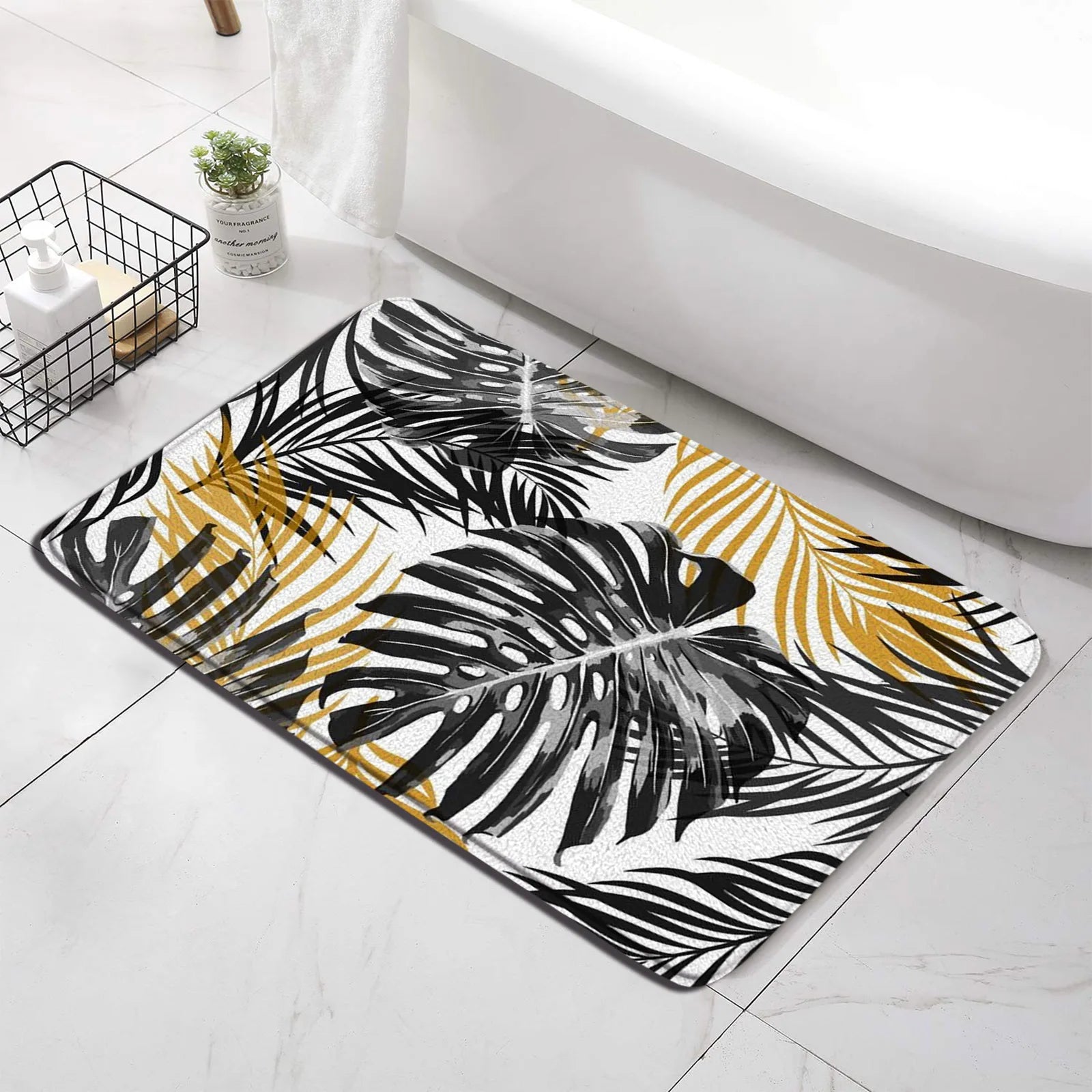 Tropical leaf bath mat with black, gold, and white palm print on bathroom floor near tub